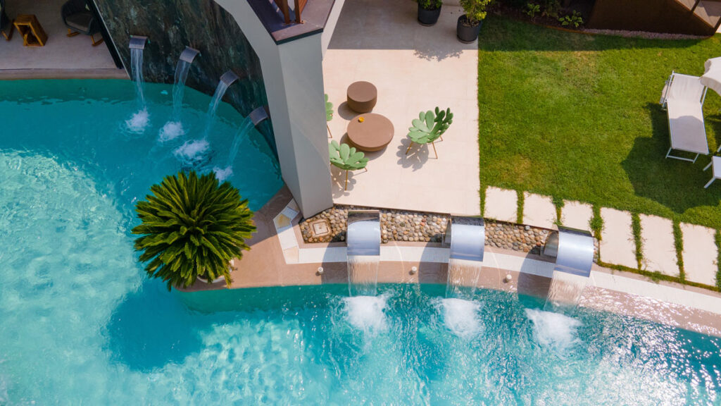 Cascate d'acqua che fluiscono nella piscina esterna con una piccola area relax adiacente all'Hotel Terme Quisisana.
