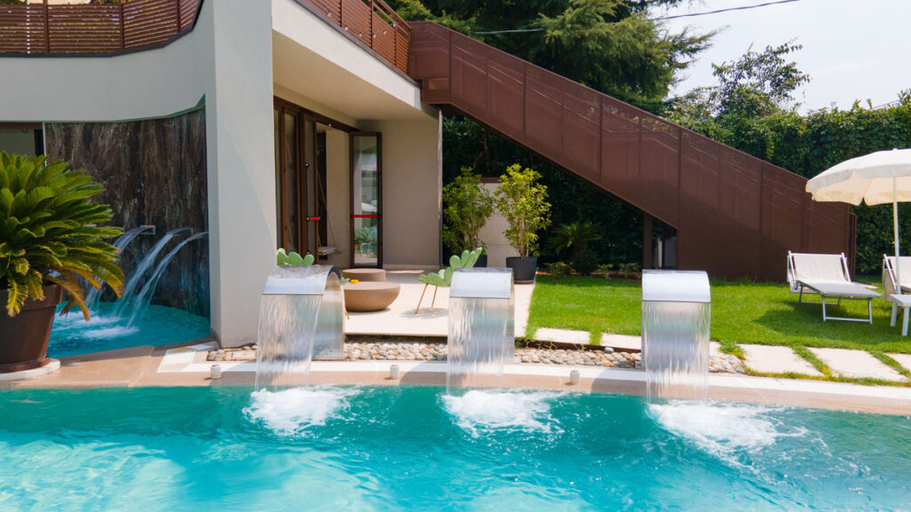 Flusso d'acqua delle cascate nella piscina esterna con vegetazione decorativa all'Hotel Terme Quisisana.