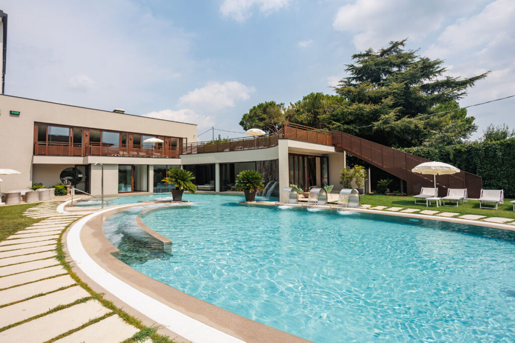 Vista laterale della piscina esterna con cascate d'acqua e area relax all'Hotel Terme Quisisana.
