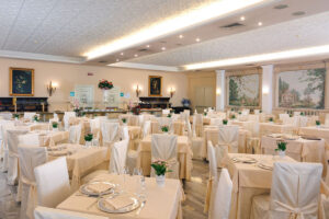 Sala del ristorante con eleganti tavoli e sedie, affreschi alle pareti, luminosa e ariosa.