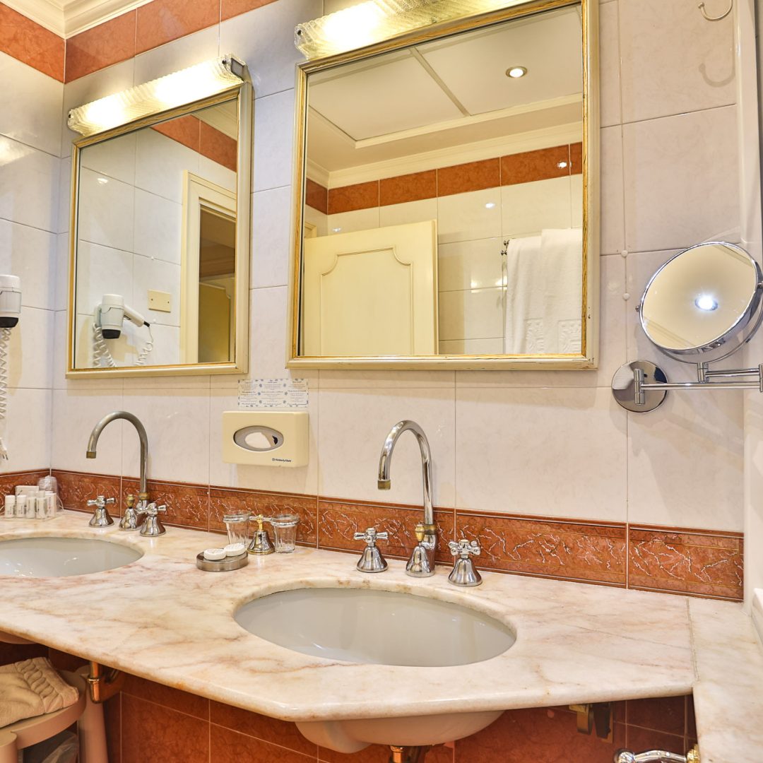 Bagno della Suite Atena con doppio lavabo in marmo e specchi dorati."