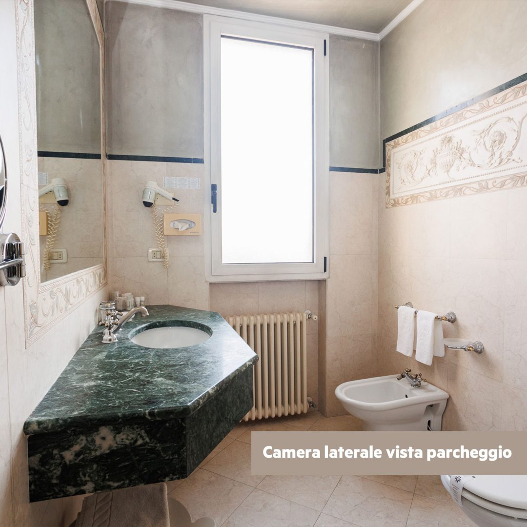 Bagno della camera Superior lato piscina con specchio ovale e dettagli in marmo giallo.