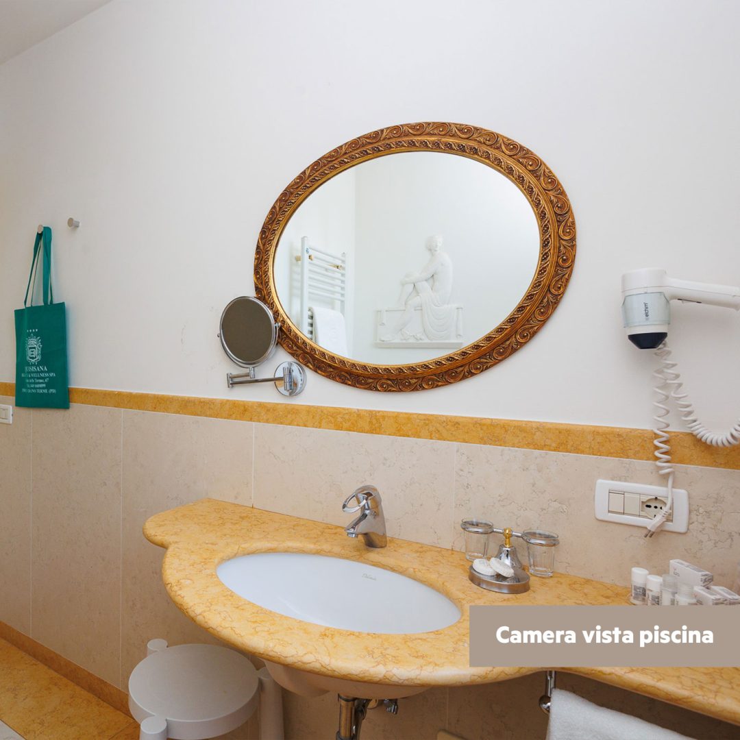 Specchio ovale dorato in bagno con lavabo in marmo giallo.