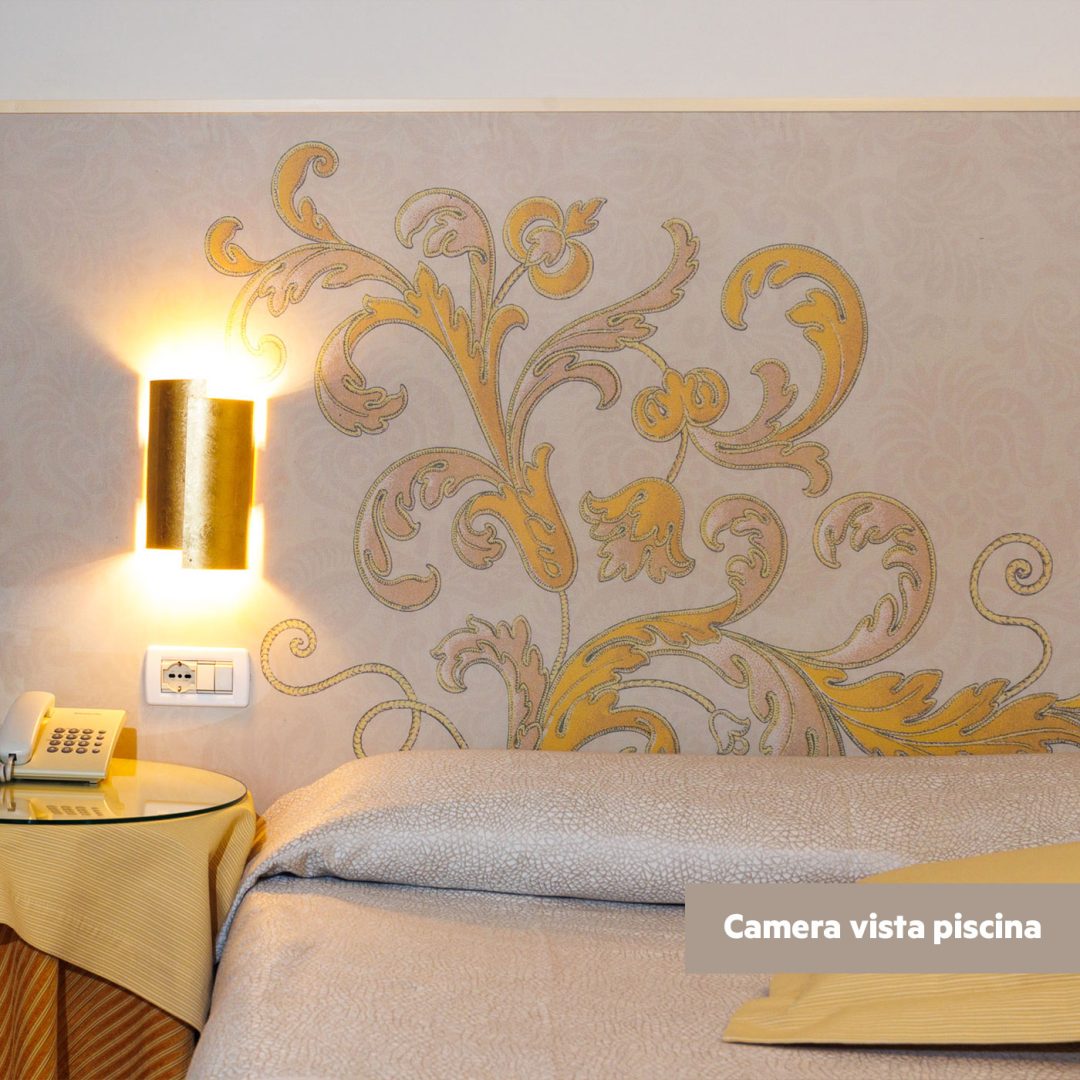 Dettaglio della testata del letto decorata con motivi dorati nella camera Superior lato piscina.
