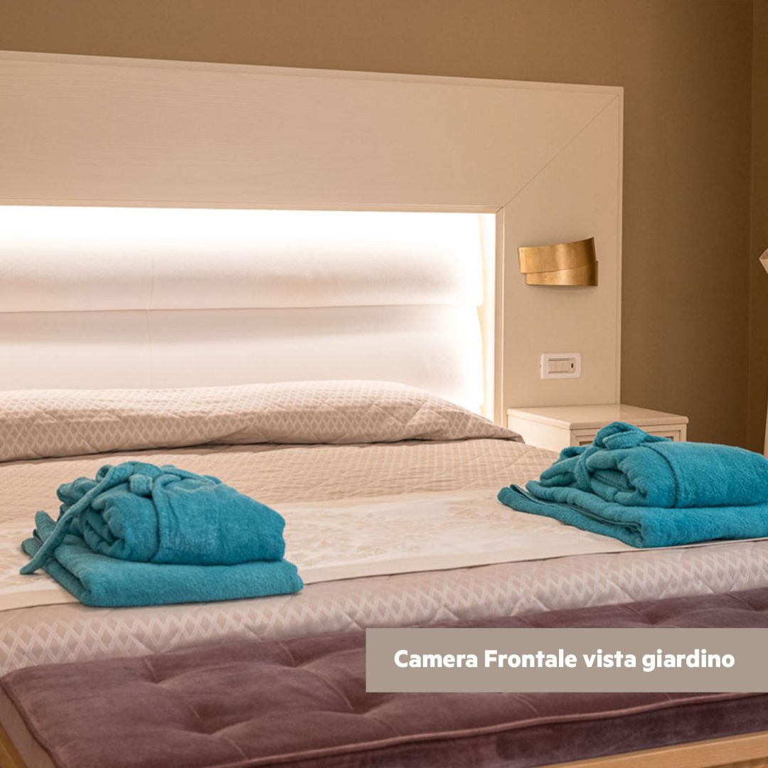 Letto matrimoniale con biancheria raffinata e accappatoi coordinati.