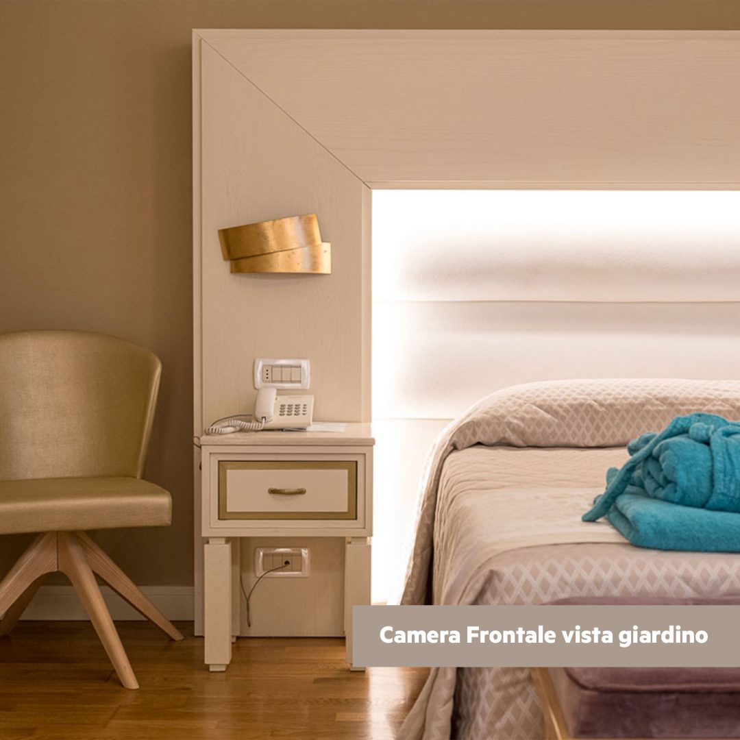 Dettaglio testata del letto con sedia di design dorata.