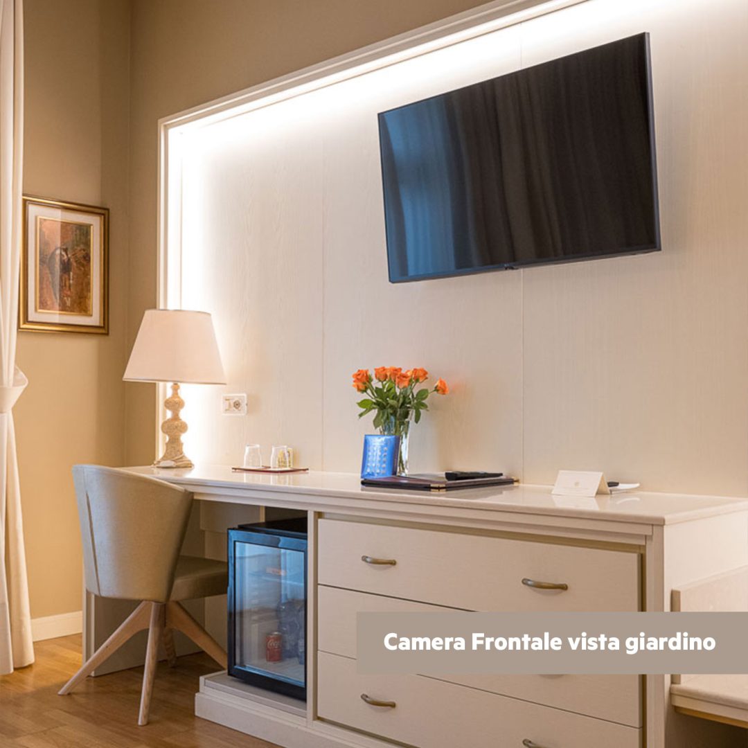 Dettaglio scrivania con minibar e fiori freschi.